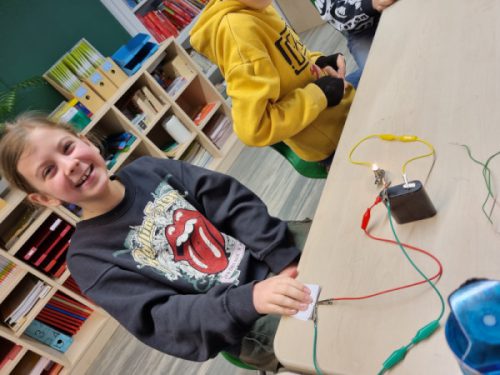 Kinder beim Experimentieren mit Batterienen Lämpchen und Kabeln