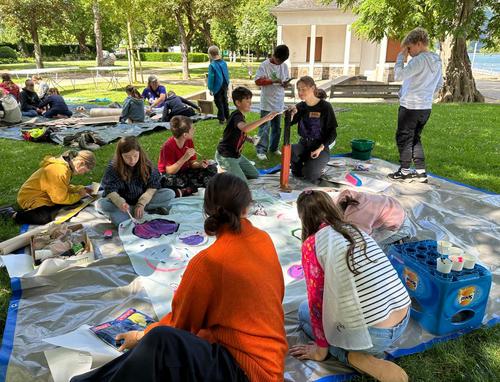 Kinder auf der Wiese am Kulturufer. Es wird gemalt und gebastelt.